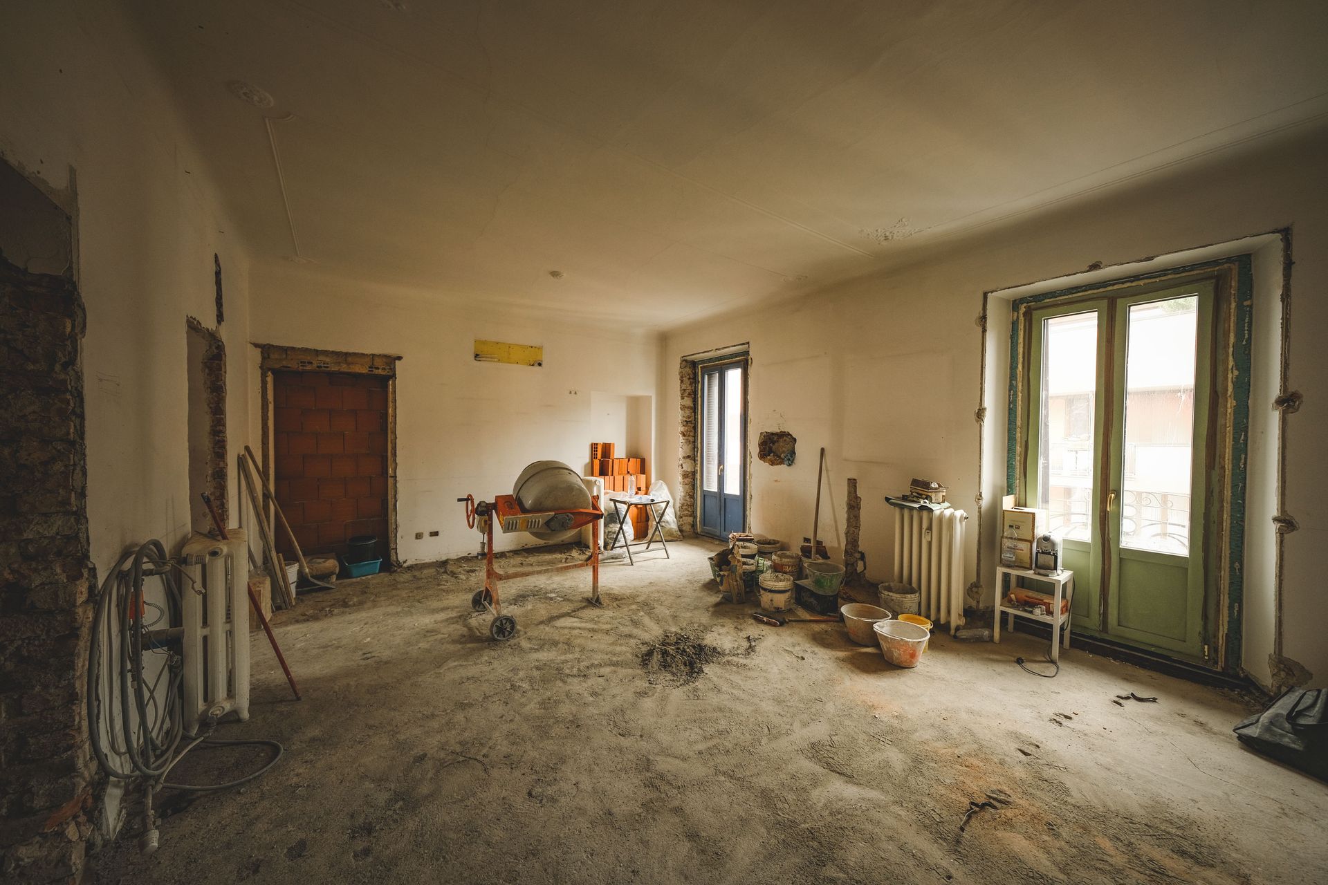 Wide view of a sunny room under renovation with construction materials and tools present, ideal for home improvement concepts.